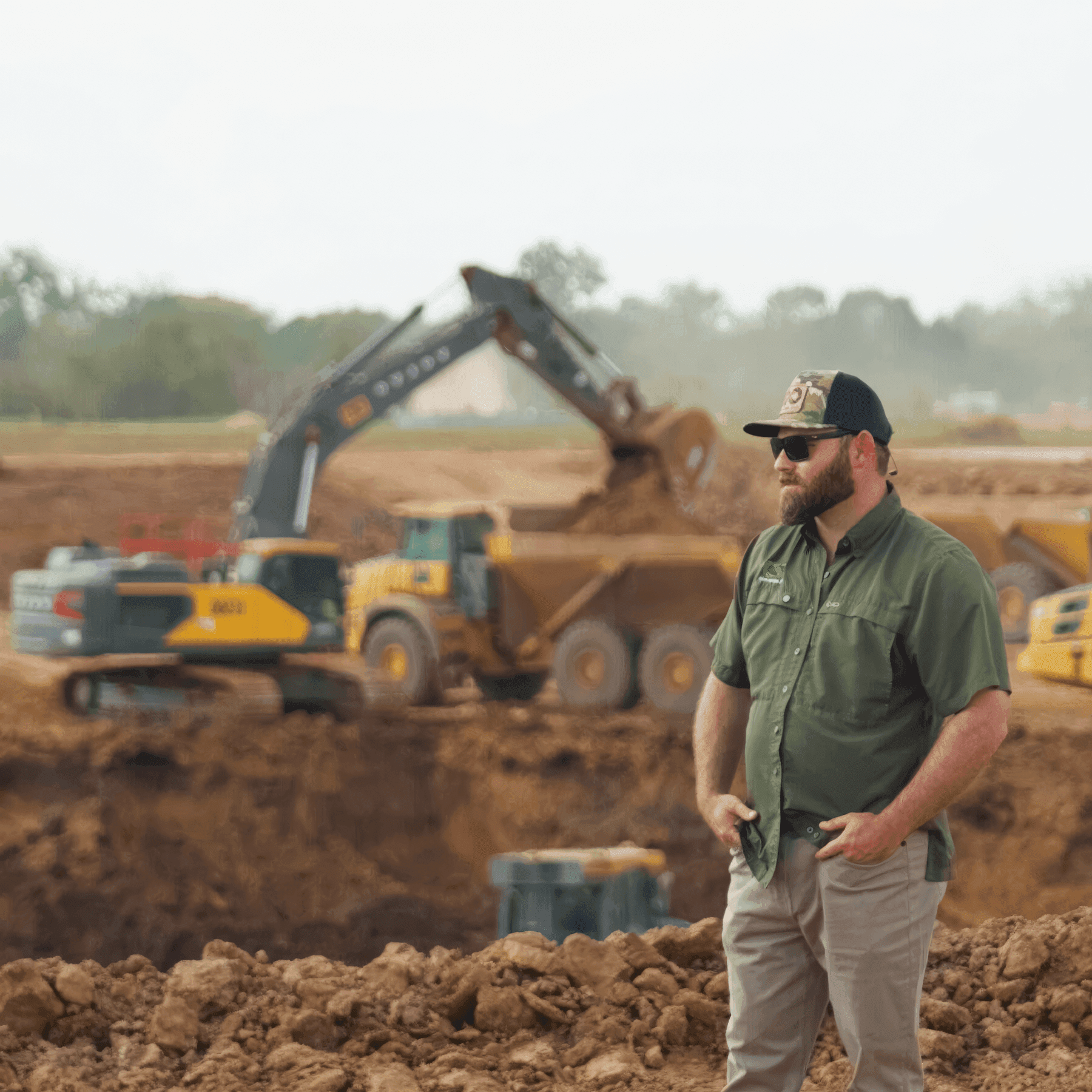 Civil Mesh founder standing on a large-scale jobsite with a drone overhead and heavy equipment moving dirt